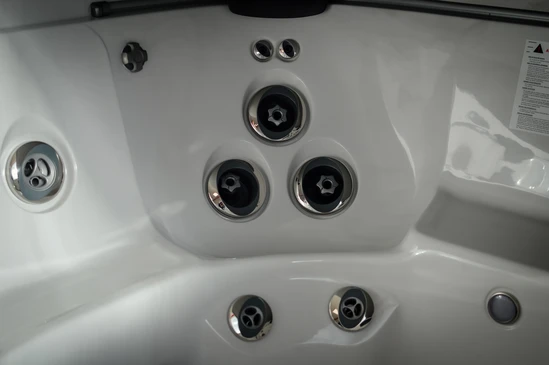 Espace aquatique extérieur avec jacuzzi circulaire en fonctionnement, jets d'hydromassage actifs créant des remous et écume blanche
