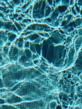 Technicien en combinaison bleue intervenant sur système de filtration piscine dans local technique bétonné